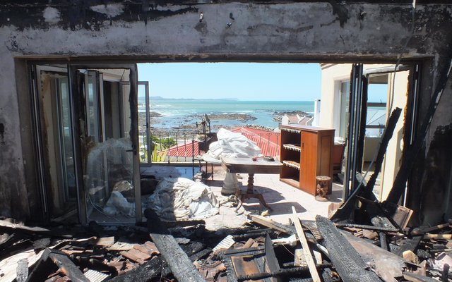 DiÃ© foto is vanuit die binnekant van die huis geneem, met die see in die agtergrond.